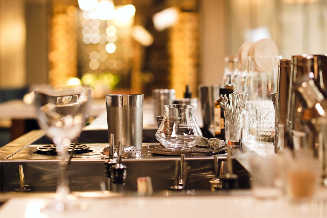 A stylish bar counter with an assortment of glassware and bar tools, perfect for cocktail preparation.